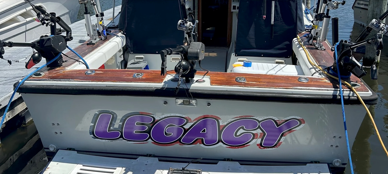 The charter boat Legacy at the dock, her purple lettering on a white hull