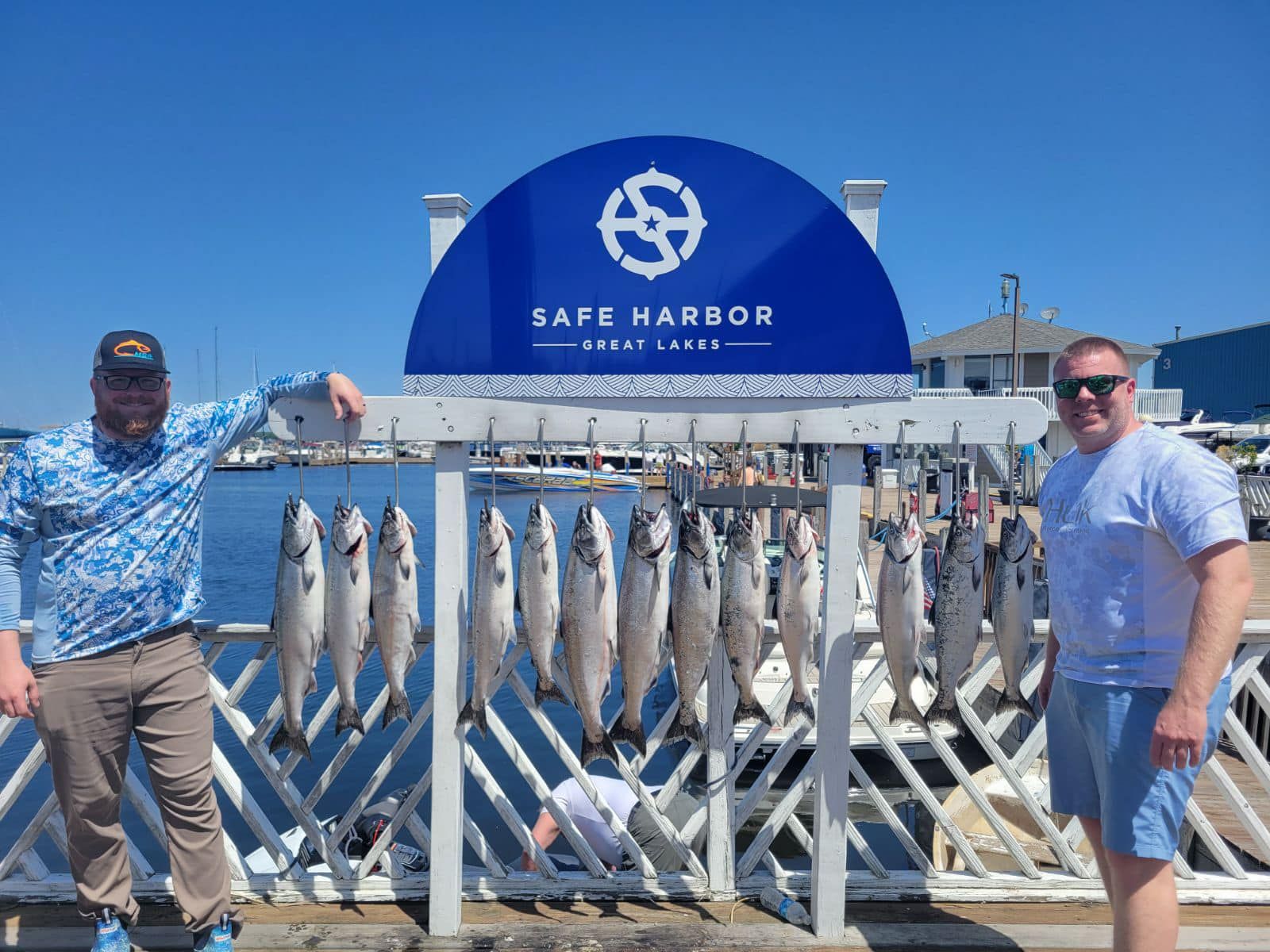 Two anglers holding lake trout at the Safe Harbor Great Lakes marina in Muskegon