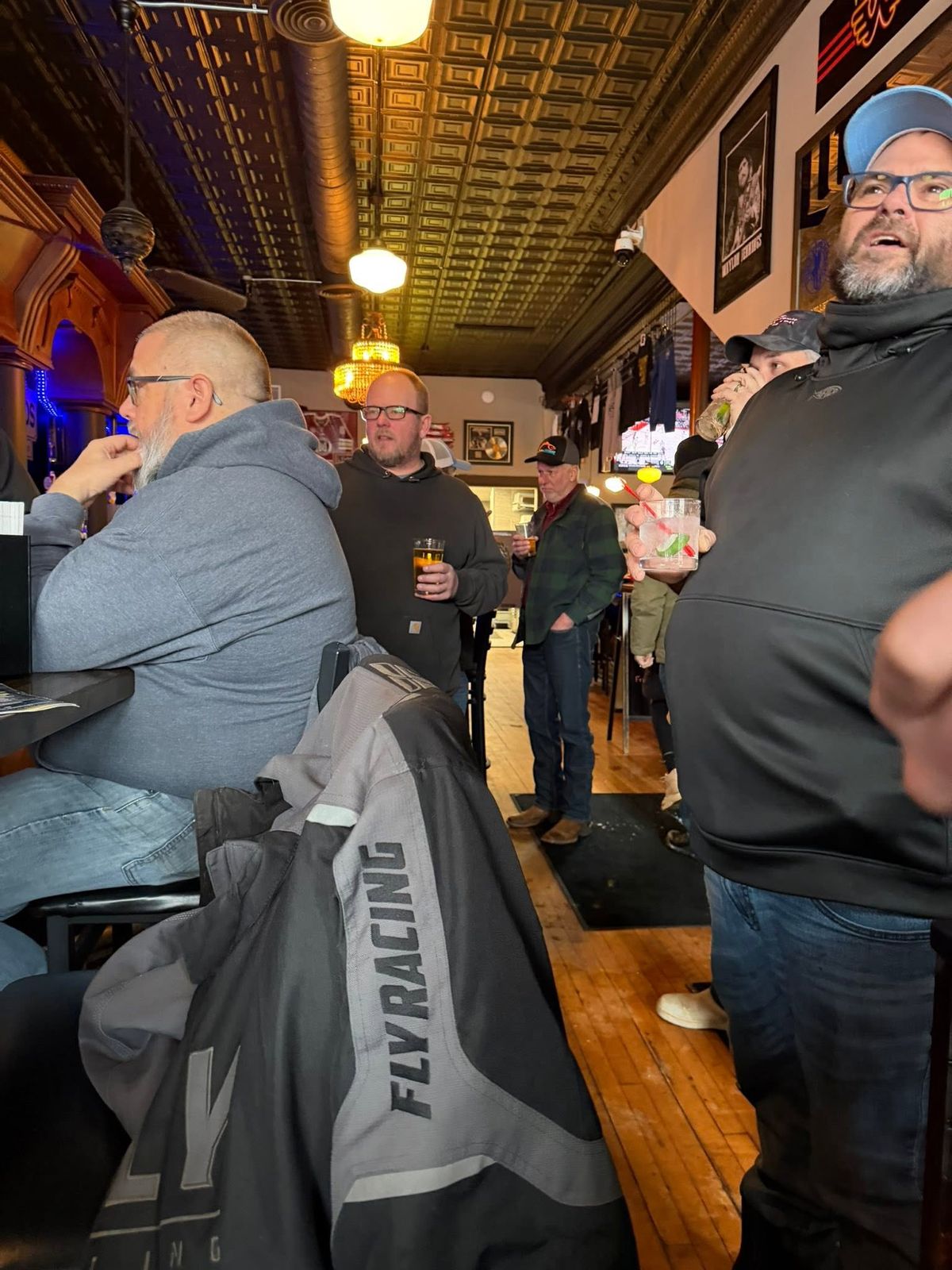 Members of the association gathered inside a bar with ornate ceiling details, talking over drinks