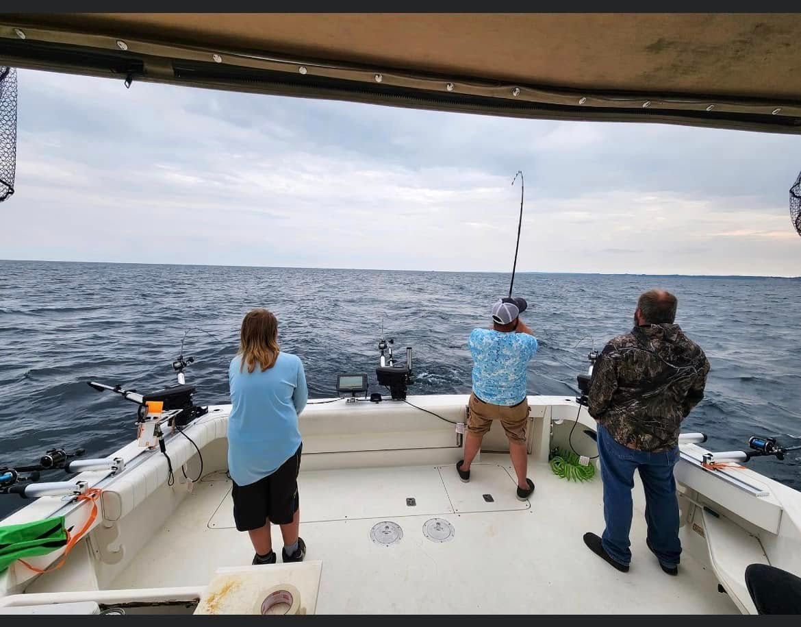 Three anglers fishing from a charter boat on calm Lake Michigan water