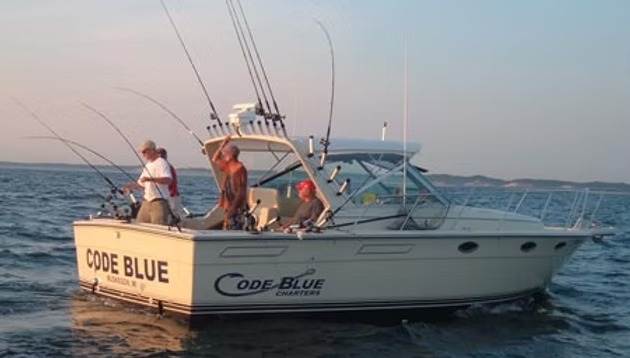 Code Blue under way at dusk with three anglers working the rods, the name painted on her bow