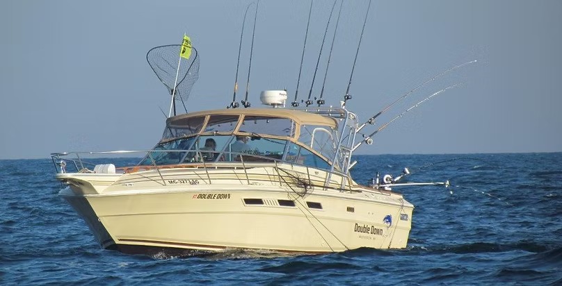 Double Down running on a flat blue lake, net up and a full spread trolling behind her