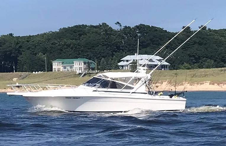 Group Therapy running close to a wooded shoreline, outriggers up and her name on the bow