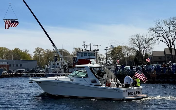 Meg-A-Fish coming through the channel under flags, her name across the transom