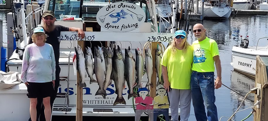 Four crew beside a full rack of king salmon under the Net Results Sport Fishing sign at the dock in Whitehall