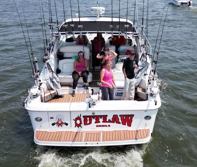 Outlaw seen from astern with a party of six aboard, her name in red across the transom