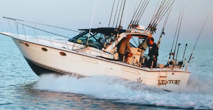 Venture powering through a swell with the crew in the cockpit and a full spread of rods out