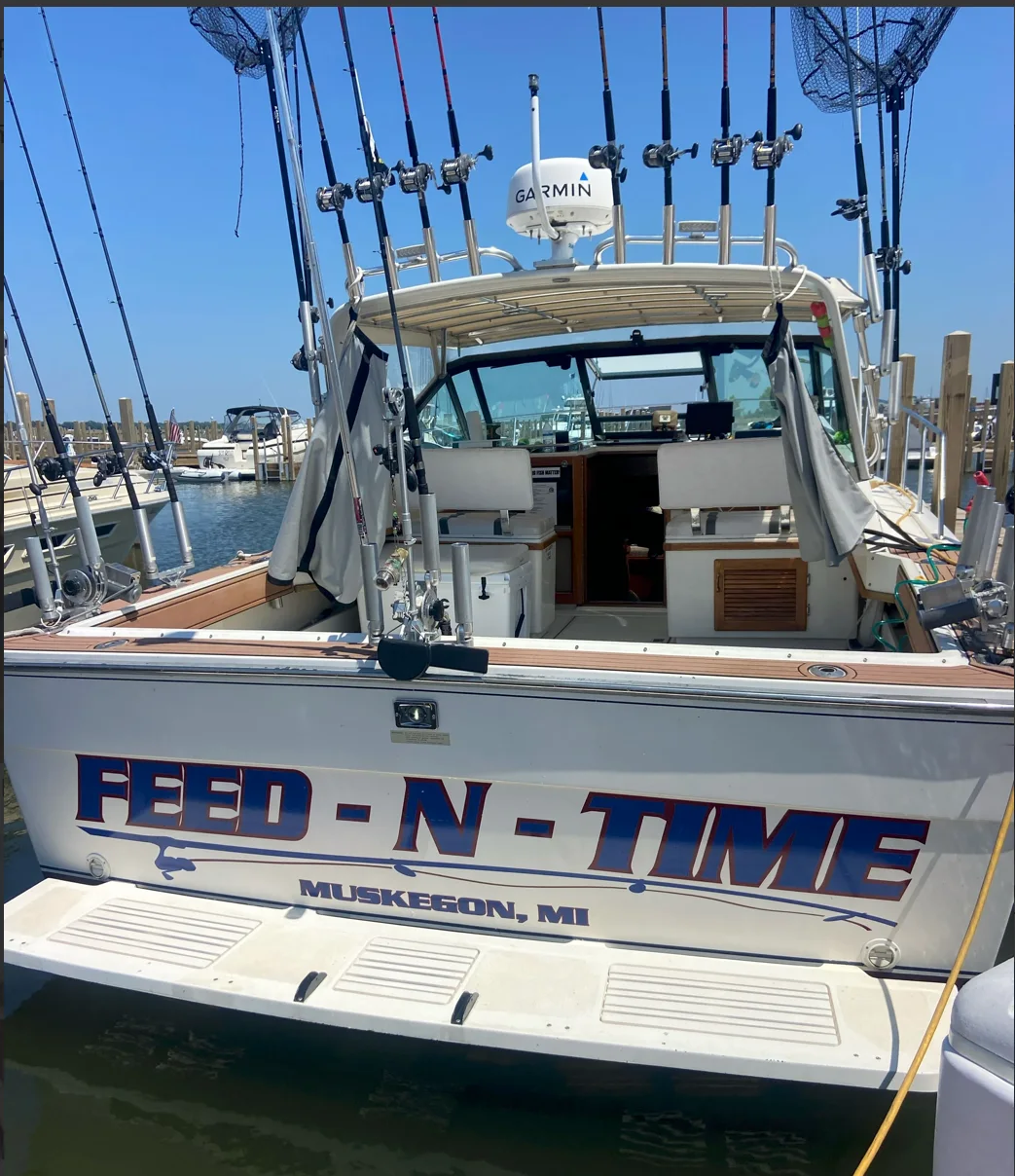 Feed-N-Time's transom at the dock, rods racked overhead and Muskegon, MI painted beneath her name