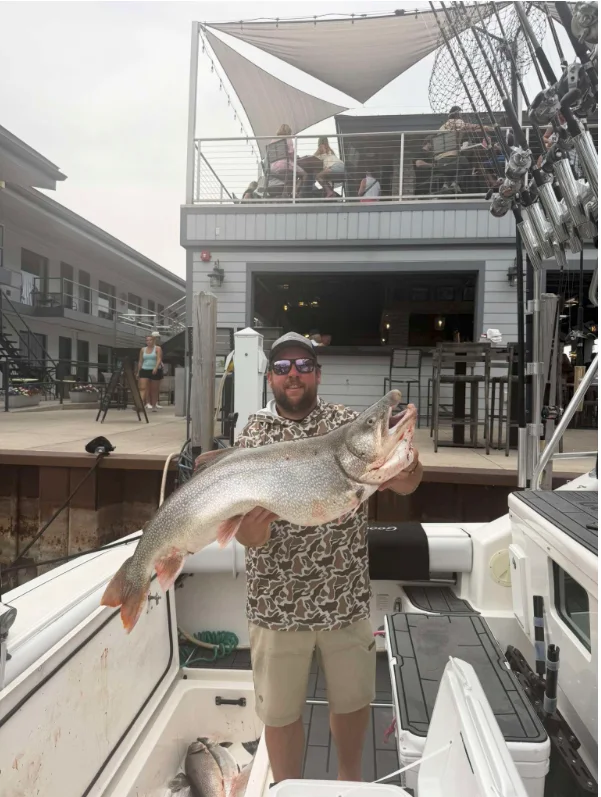 A charter captain aboard his boat in Muskegon waters holding up the MCBA big fish belt