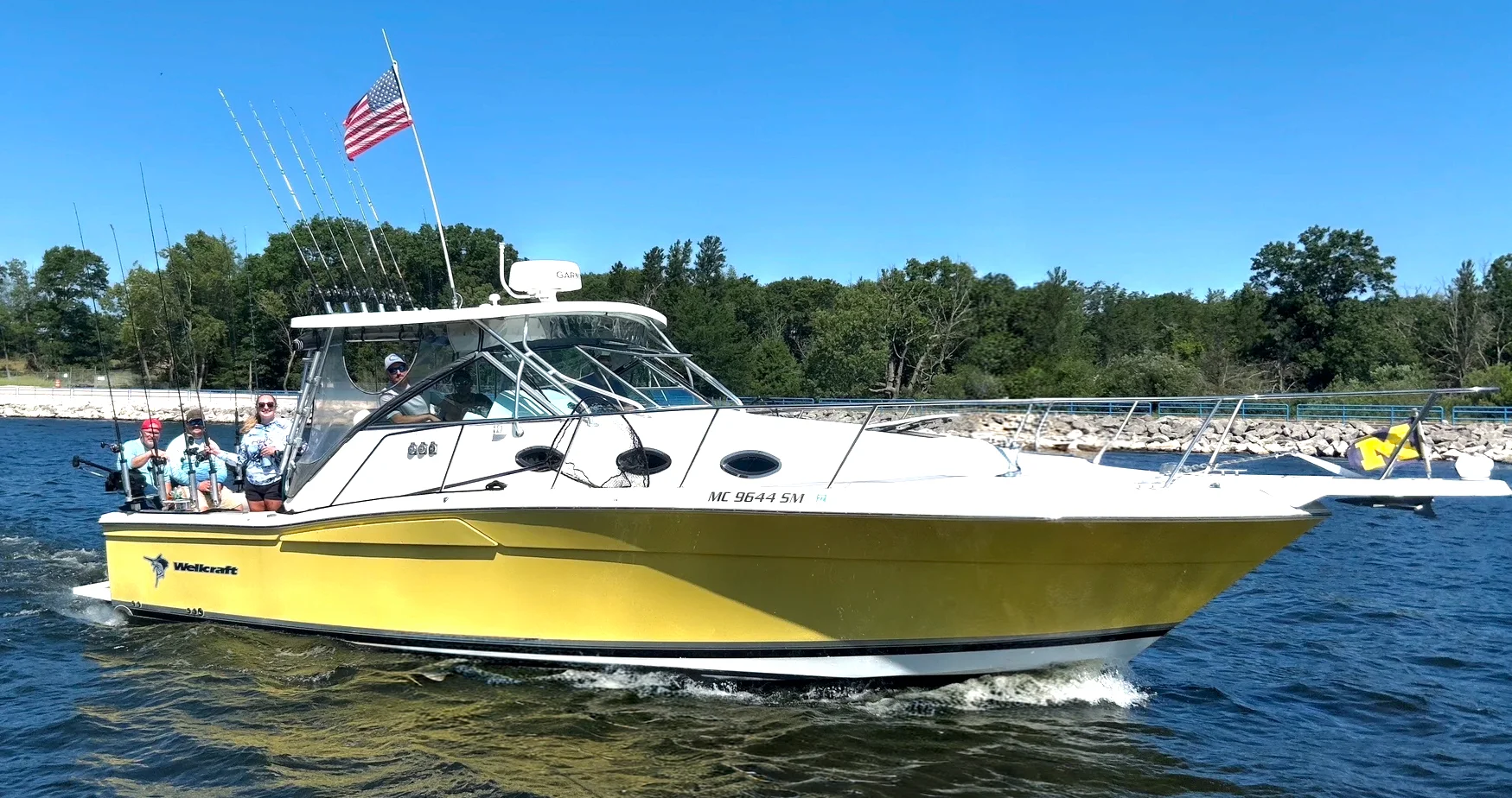 Tagged Out Sportfishing's yellow-hulled boat running through the channel with rods out and a crew aboard